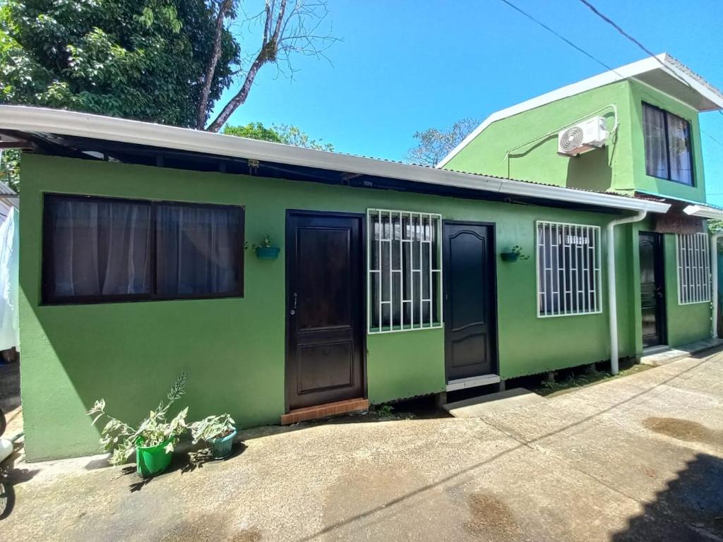 托尔图格罗Apartamentos Caimán Tortuguero的绿色房子,设有黑色门窗