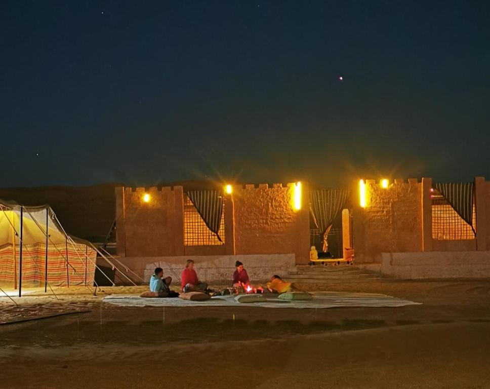 Ḩawīyah沙漠奇观营地酒店的一群人晚上坐在地上