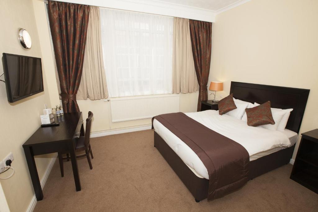 斯旺西海豚SA1酒店的一间卧室配有一张床、一张书桌和一个窗户。