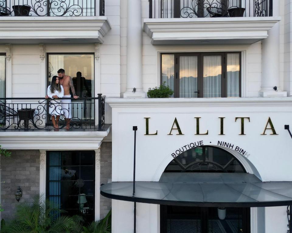 宁平Lalita Boutique Hotel & Spa Ninh Binh的一对夫妇站在大楼前的阳台