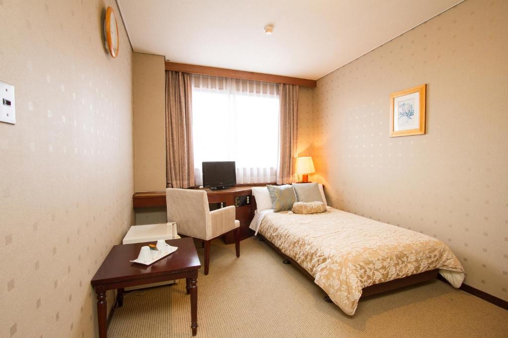 北九州Shohakuen Hotel的配有一张床、一张书桌和一扇窗户的酒店客房