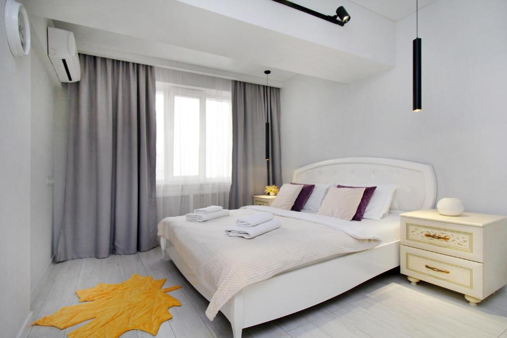 阿拉木图уютная квартира-студия в центре Алматы的白色卧室配有大白色床和粉红色枕头