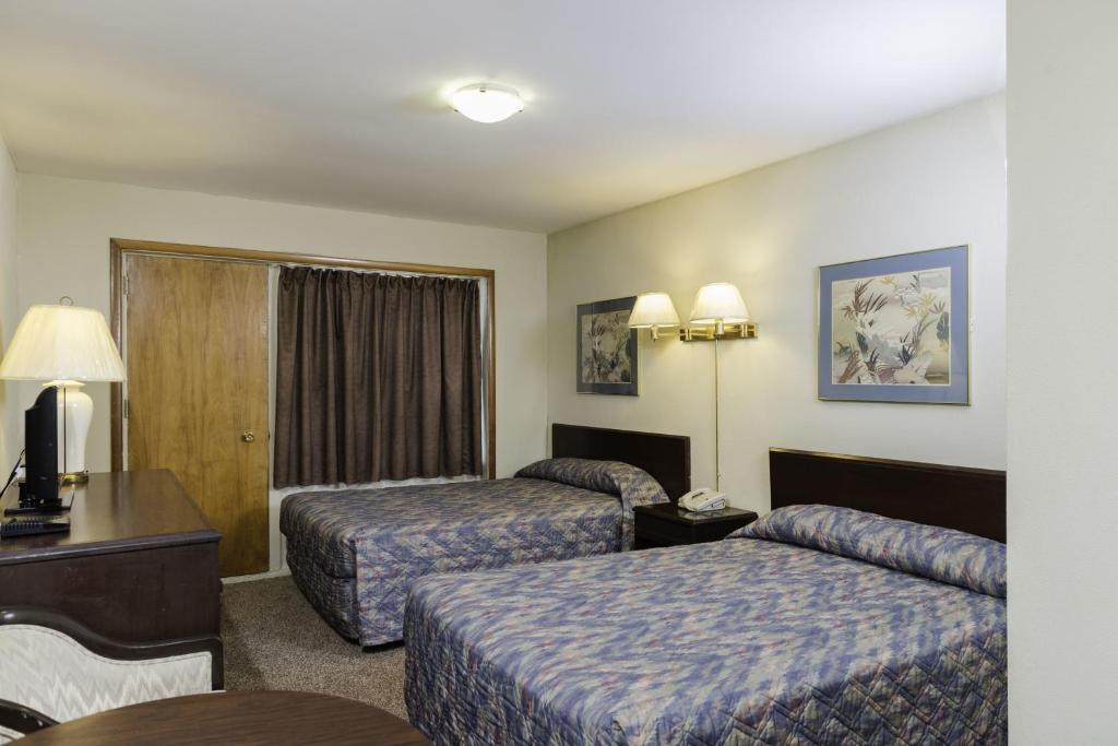 温尼伯骑士宾馆的酒店客房设有两张床和一张桌子。