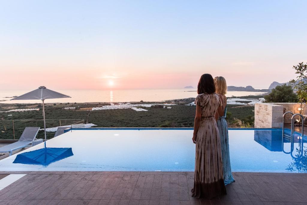 法拉萨纳Falasarna Luxury Villas的站在游泳池旁的女人,看着日落