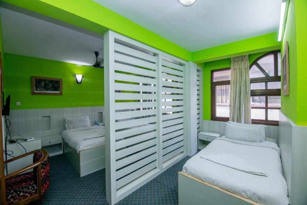 加德满都柚子之家酒店的一间卧室设有绿色的墙壁、一张床和一张书桌