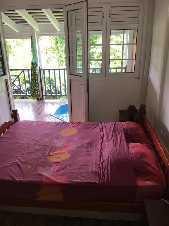 法兰西堡LOFT ET VERDURE的一间卧室配有一张带紫色棉被的床