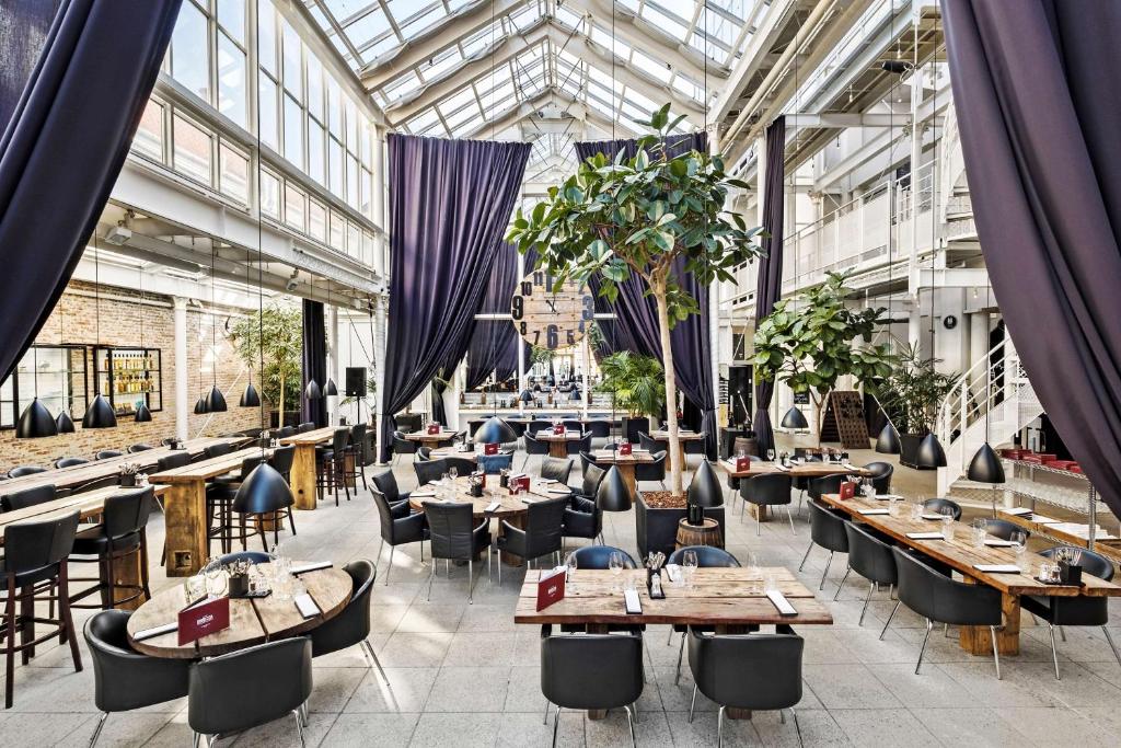 瓦埃勒Best Western ToRVEhallerne的餐厅设有桌椅和玻璃天花板