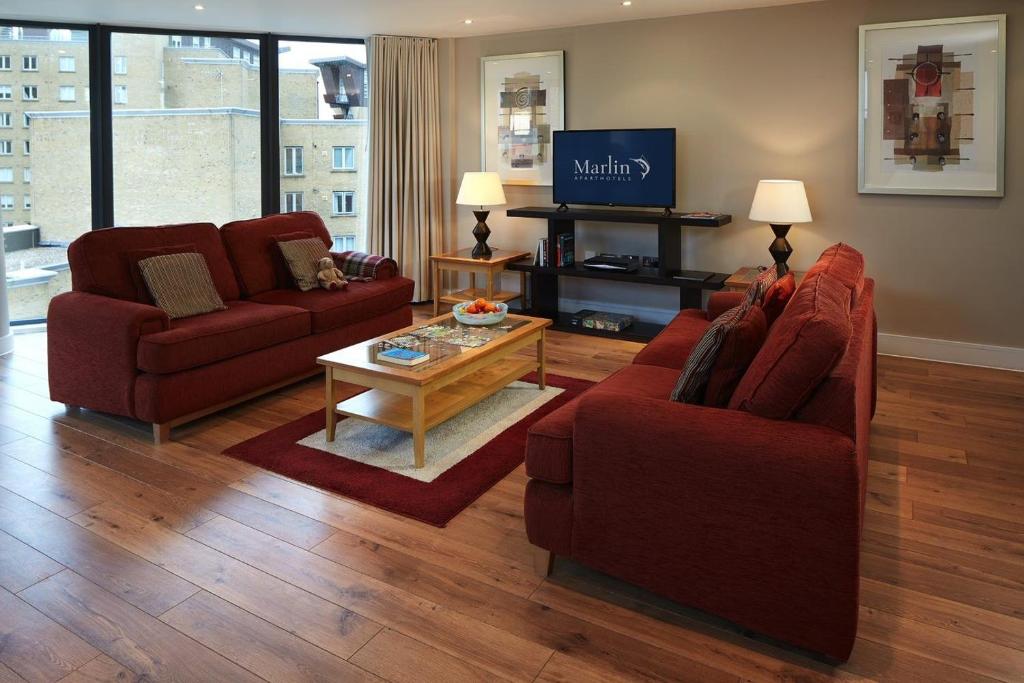 伦敦Marlin Canary Wharf的客厅配有2把红色椅子和咖啡桌