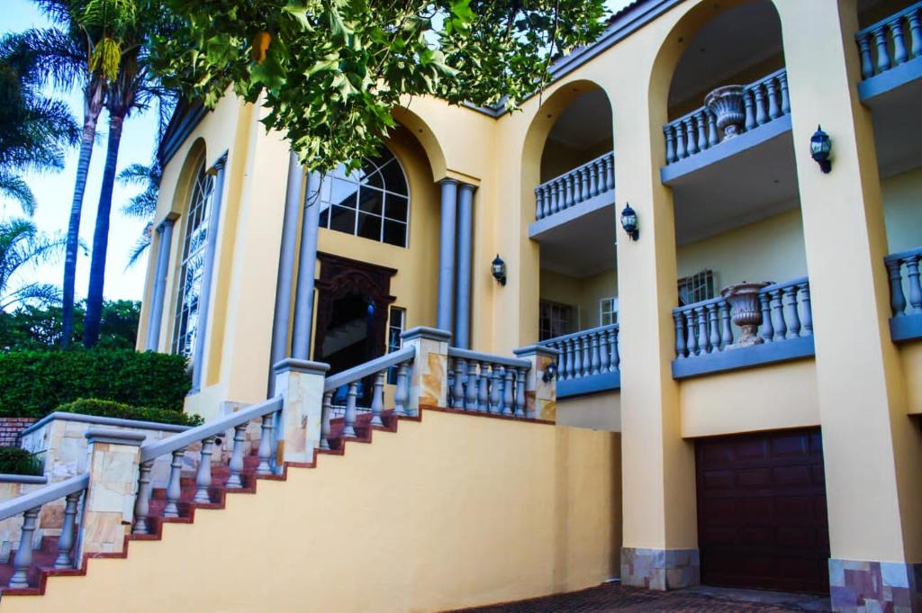 比勒陀利亚TDM's Boutique Guest House的黄色房子,有楼梯和棕榈树