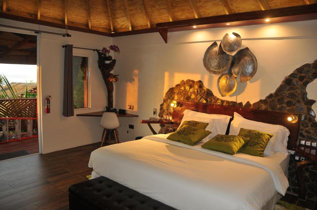 Saint Joseph芒果岛小屋酒店的卧室配有带绿色枕头的大型白色床