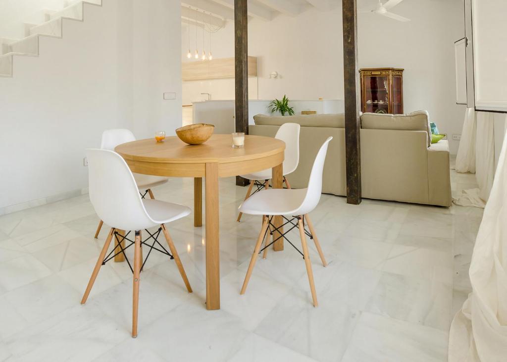 塔里法El Erizo Apartamentos的一间带木桌和白色椅子的用餐室