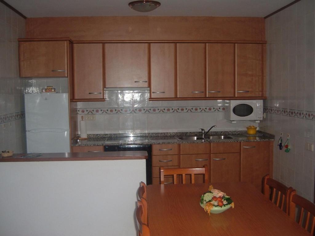 Durro卡德尔帕索尔公寓的厨房配有木制橱柜和一张带一盘食物的桌子。