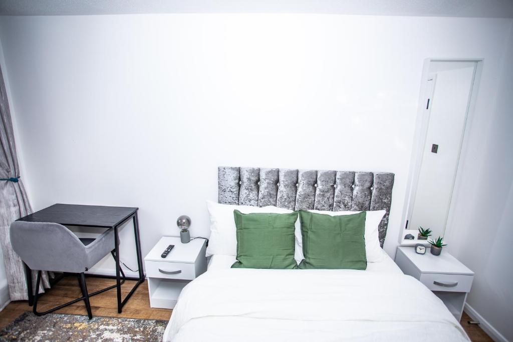 Thamesmeadla vida in casa的一间卧室配有一张带绿色枕头的床和一张书桌