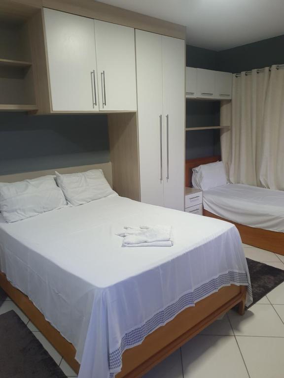 维拉维尔哈SUÍTE PRAIA DE ITAPARICA的一间卧室设有两张床和白色橱柜。