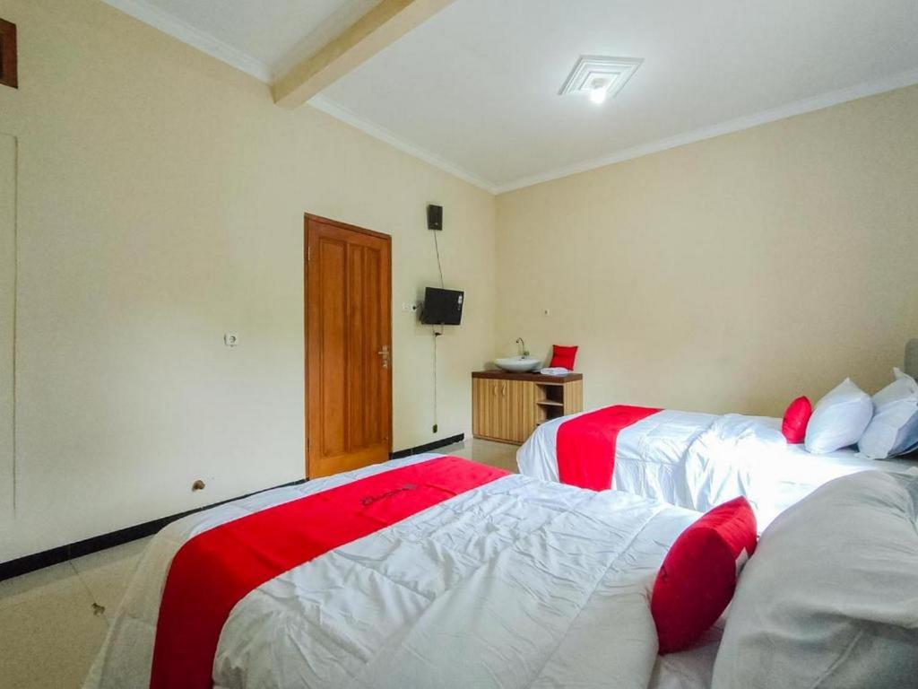 KisaranRedDoorz @ Kisaran Kota的一间卧室配有两张红色和白色床单
