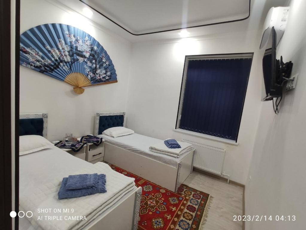 布哈拉KAMIR Guest House的小房间设有两张床和窗户