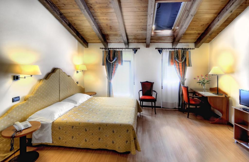 马焦雷堡Antica Locanda Il Sole的一间卧室配有一张床、一张书桌和一台电视