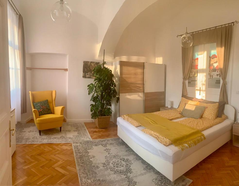 埃格尔Forst-Ház Apartman的一间卧室配有一张床和一张黄色椅子