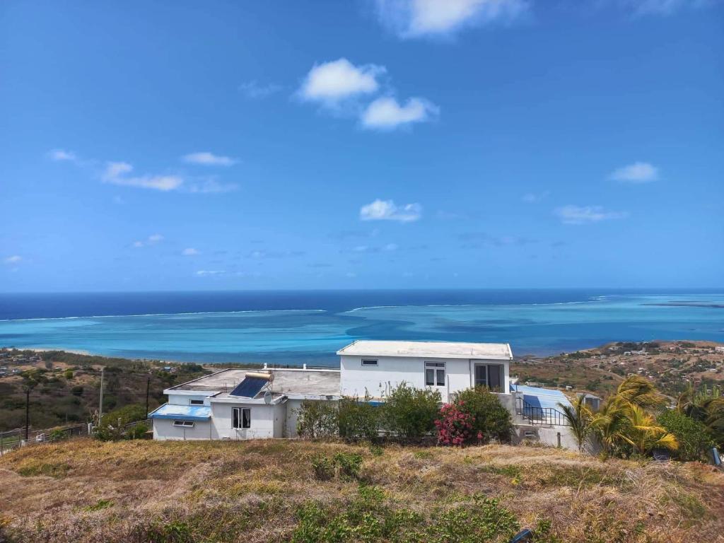 Rodrigues IslandÔ Bercail du Sud chez Jeannette的一座山丘上的房屋,背景是大海