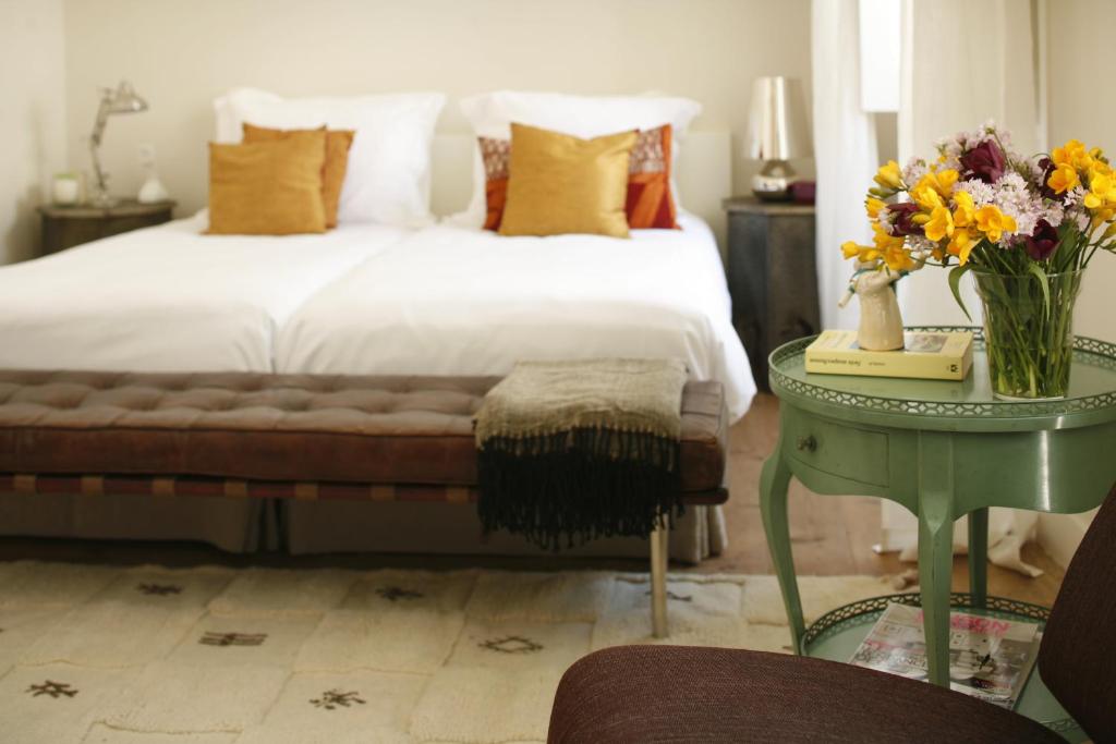 里斯本Casa das Janelas com Vista的一间卧室配有一张床和一张花瓶桌子