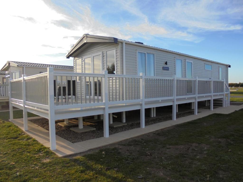 梅布尔索普6 Berth Grange Leisure Park Mablethorpe Stonewood的移动房屋设有门廊和白色栏杆