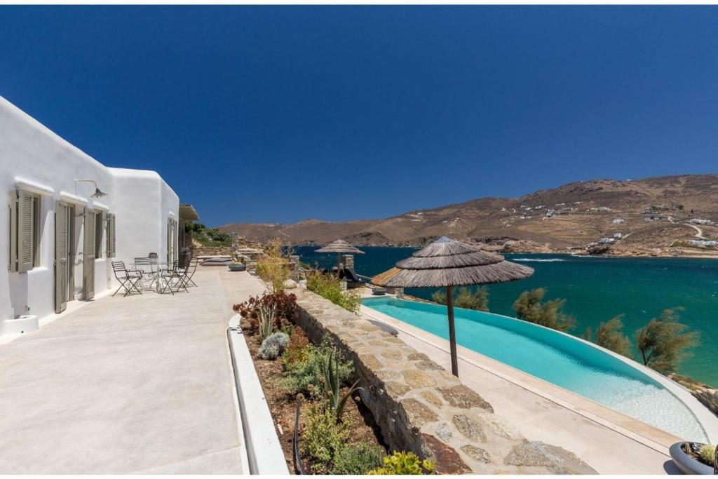 DexamenesElite Mykonos Villa - Villa Roxane - Private Pool - 6 Bedrooms - Beachfront - Ftelia的一座带游泳池和遮阳伞的房子