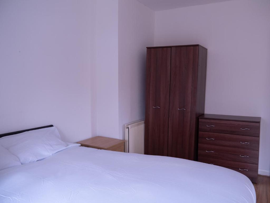 伯明翰Convenient 3BR close to QE Hospital & University of Birmingham的一间卧室配有一张床和一个木制橱柜
