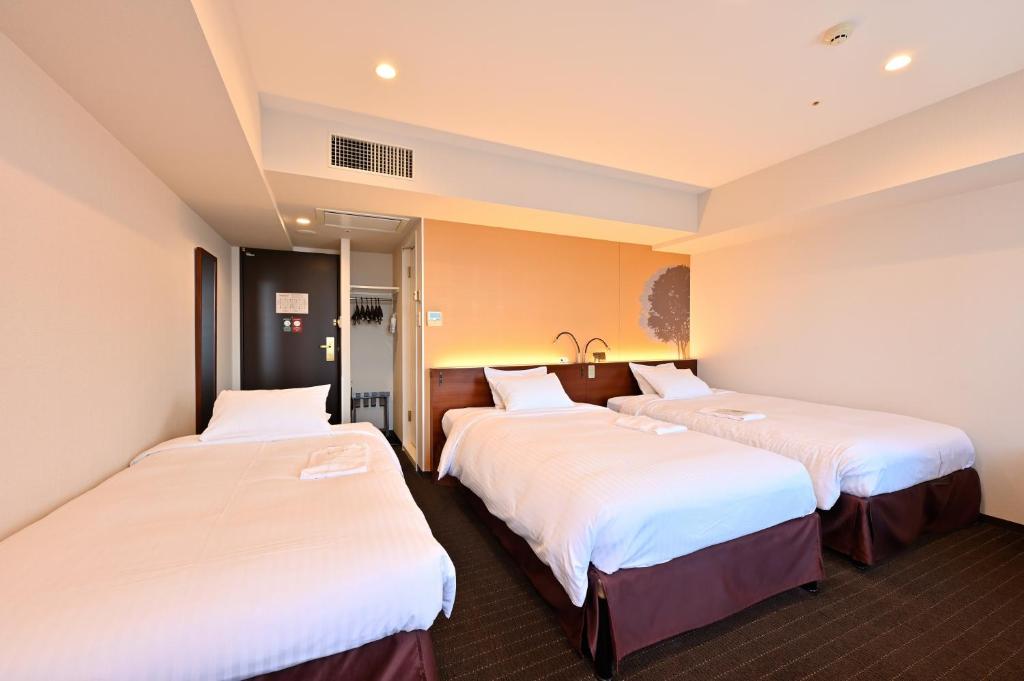 札幌札幌京阪酒店的配有白色床单的酒店客房内的两张床