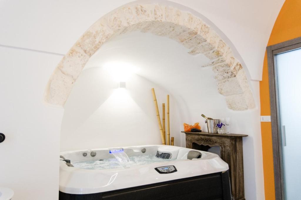 奥斯图尼Ostuni Luxury Room的浴缸位于带拱门的房间