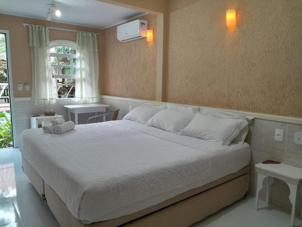 瓜皮米林Pousada Nascente Pequena的一间卧室配有一张带白色床单的大床