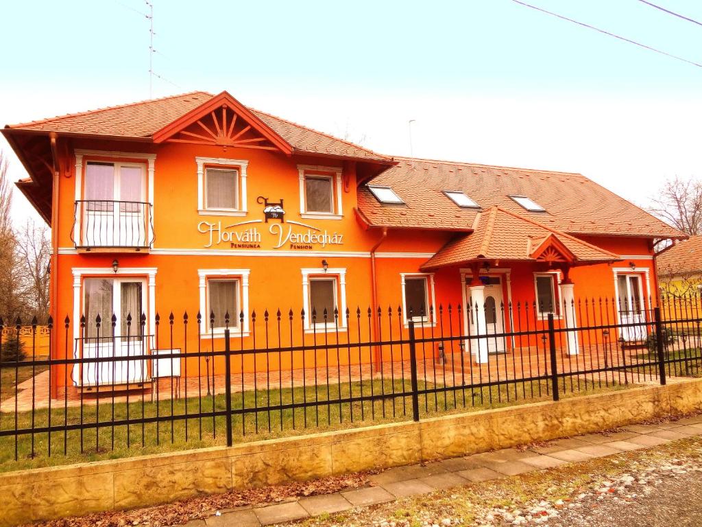 欧罗什哈佐Horváth Vendégház的一座橙色房子,前面有黑色的围栏