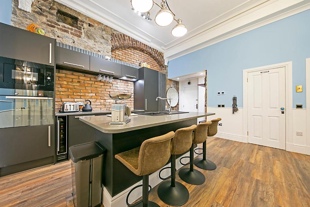 阿伯丁Market Street Apartments ✪ Grampian Lettings Ltd的厨房设有带凳子和砖墙的酒吧