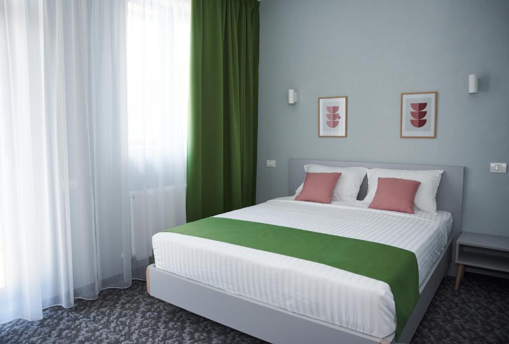 克利默内什蒂Astra Hotel的一间卧室配有一张带绿色窗帘的大床