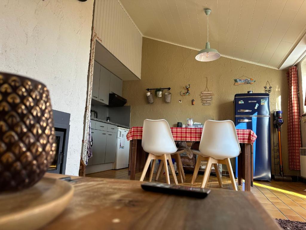 维尔通Le petit Rabais的厨房配有桌子和3把白色椅子