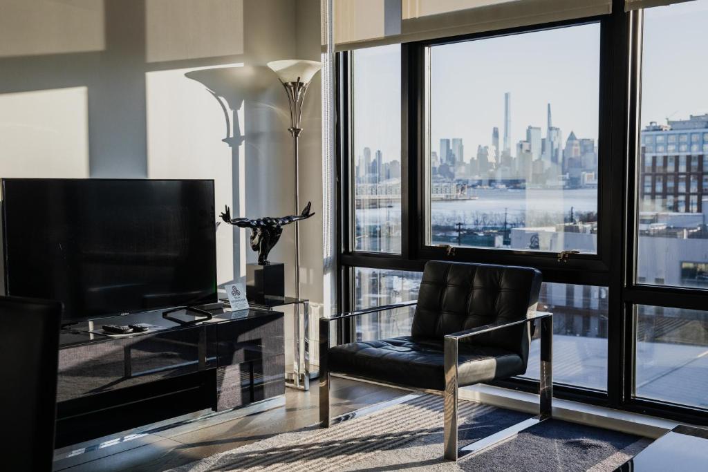 霍博肯Dharma Home Suites Hoboken的客厅配有椅子和大窗户