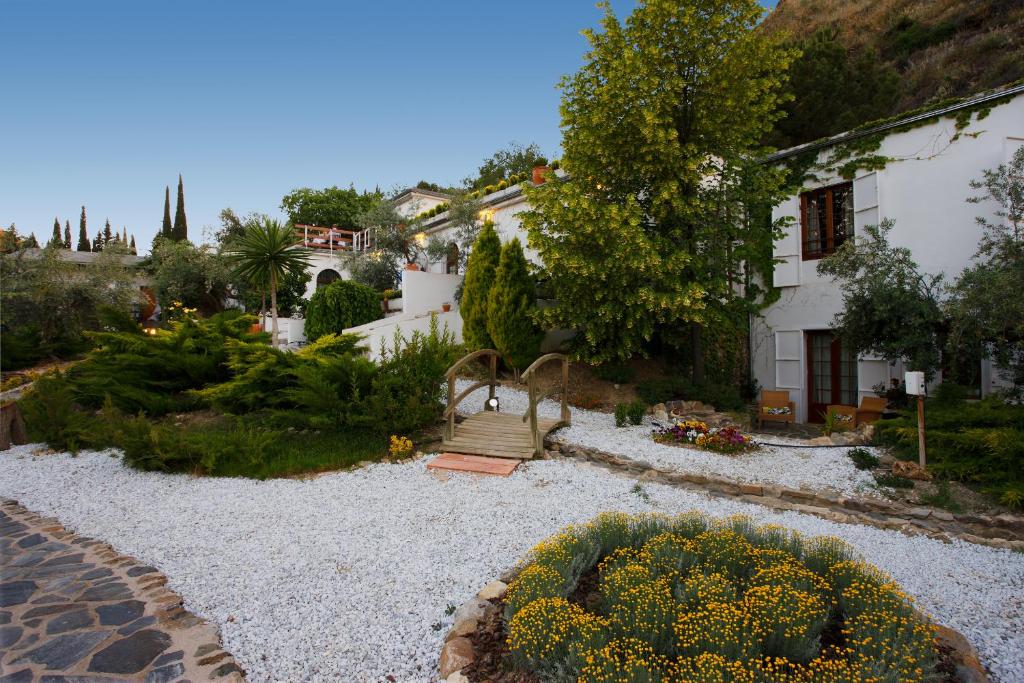 莫纳奇尔阿尔穆尼亚山谷酒店的一座带房子的花园和一个种有黄色花卉的花园