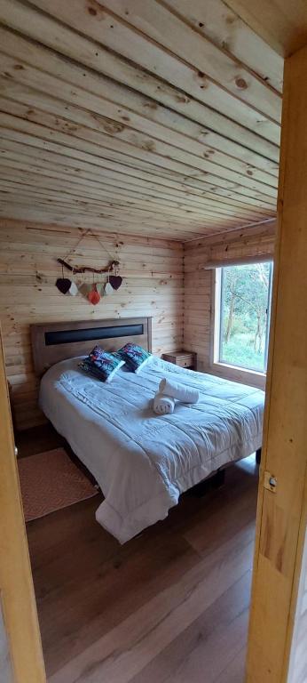 科查莫Cabaña La Troya的小木屋内一间卧室,配有一张床