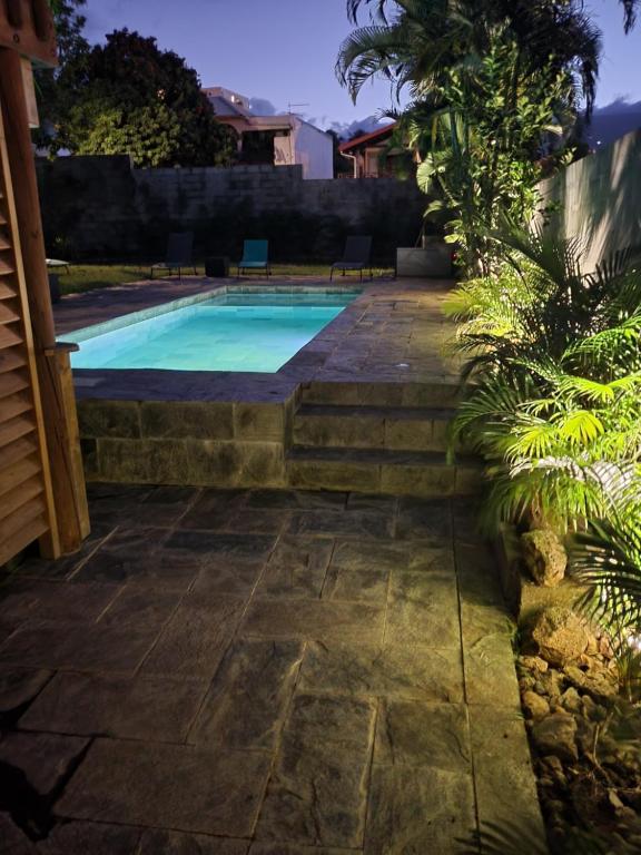 圣玛丽Rez-de-chaussée indépendant avec piscine的一座房子旁的游泳池,设有石头走道