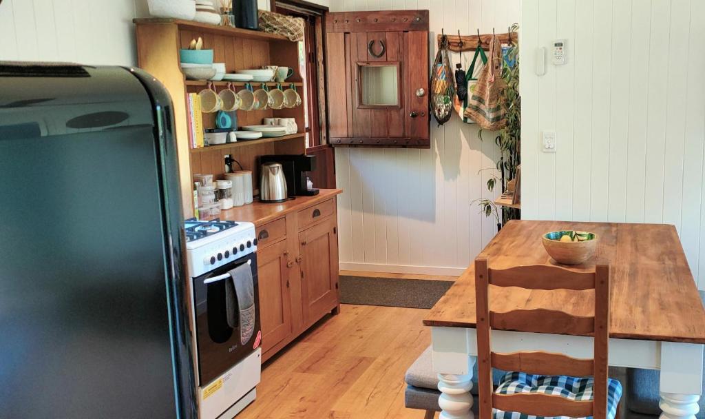 旺加瓦兰Woodmans Cottage 24, Gold Coast Hinterland的厨房配有木桌和冰箱。