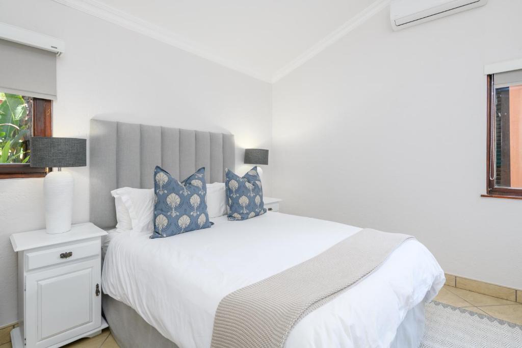 绍斯布鲁姆San Lameer Villa 3207 - 3 Bedroom Superior - 6 pax - San Lameer Rental Agency的白色卧室配有一张带蓝色枕头的大床