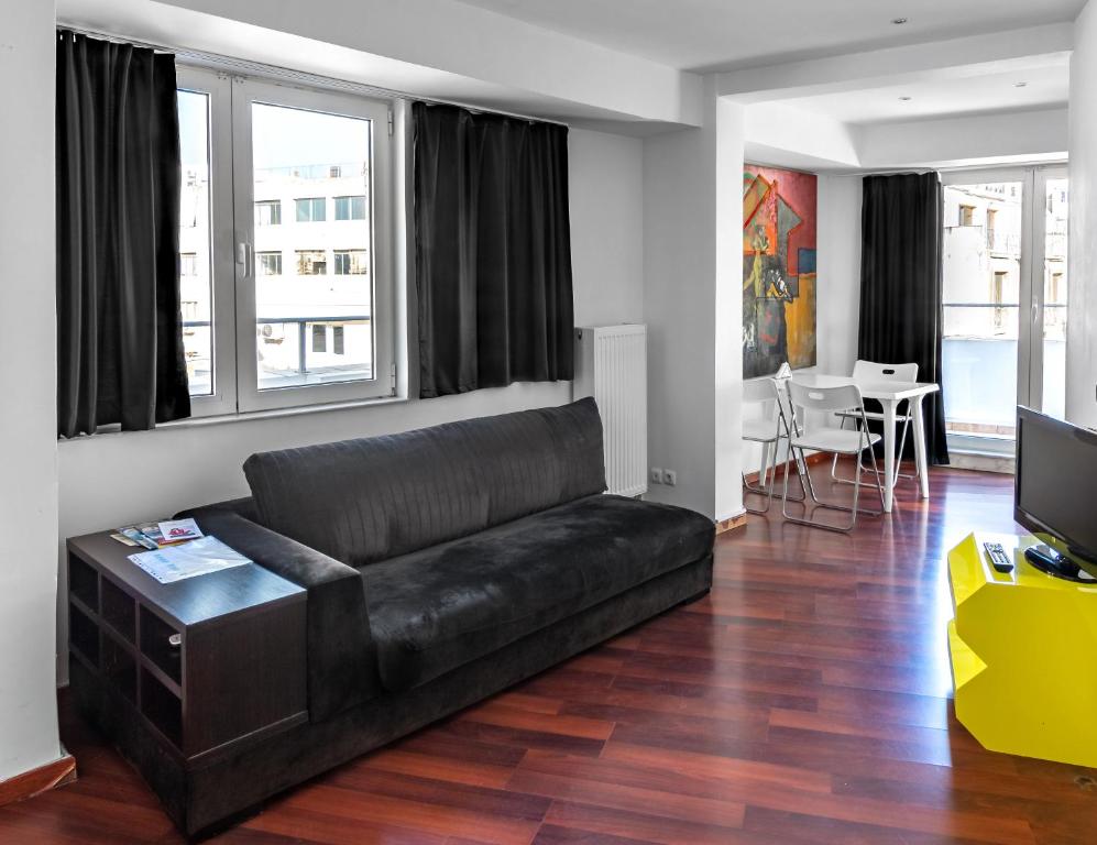 雅典Loft的客厅配有黑色真皮沙发和电视