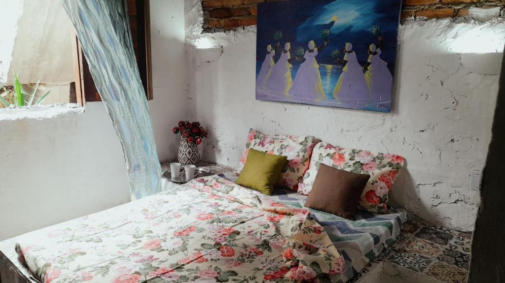 伊列乌斯Pousada Rainha das Águas的卧室配有一张床,墙上挂有绘画作品