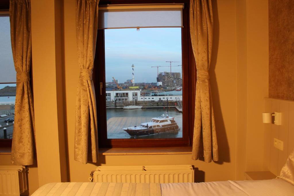 奥斯坦德Hotel Rubens的一间卧室,设有窗户,水中有一条船