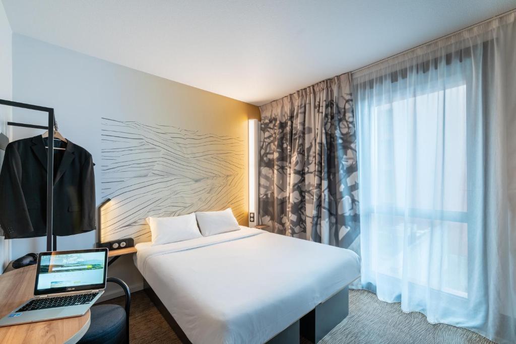 阿斯克新城B&B HOTEL Lille Grand Stade的酒店客房配有一张床铺和一张书桌上的笔记本电脑
