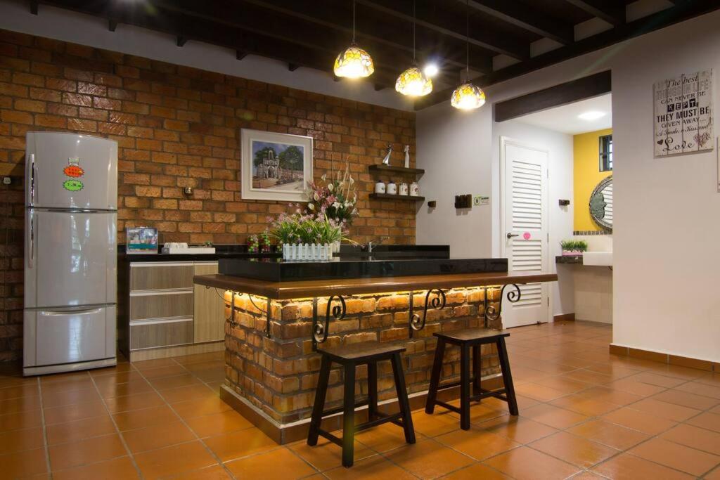 马六甲Harmonia Homestay的厨房设有带凳子和冰箱的酒吧。