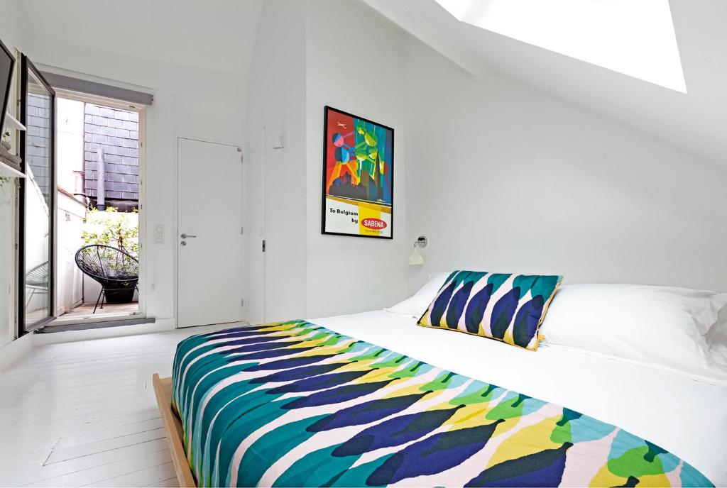 布鲁塞尔幸福旅馆的一间卧室配有一张带彩色毯子的床
