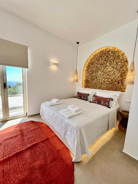 皮尔戈斯Thealos Santorini ( close to square)的白色卧室配有一张红色地毯的大床