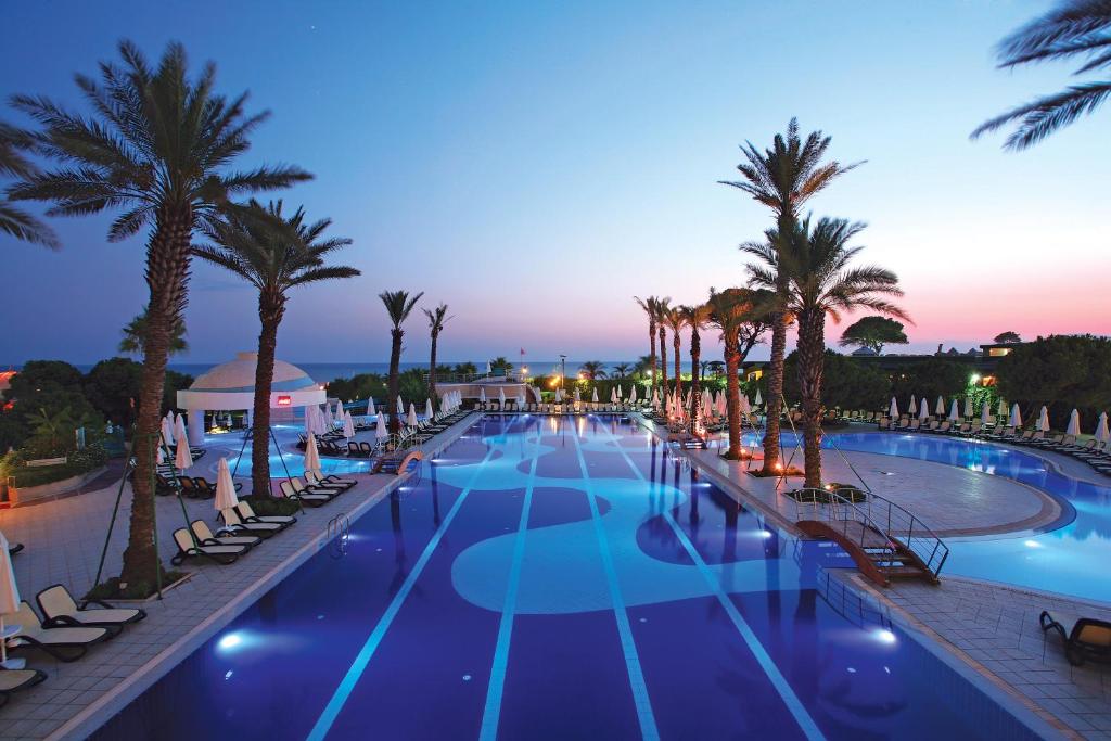 贝莱克Limak Atlantis Deluxe Hotel Belek的一座棕榈树和椅子的大型游泳池