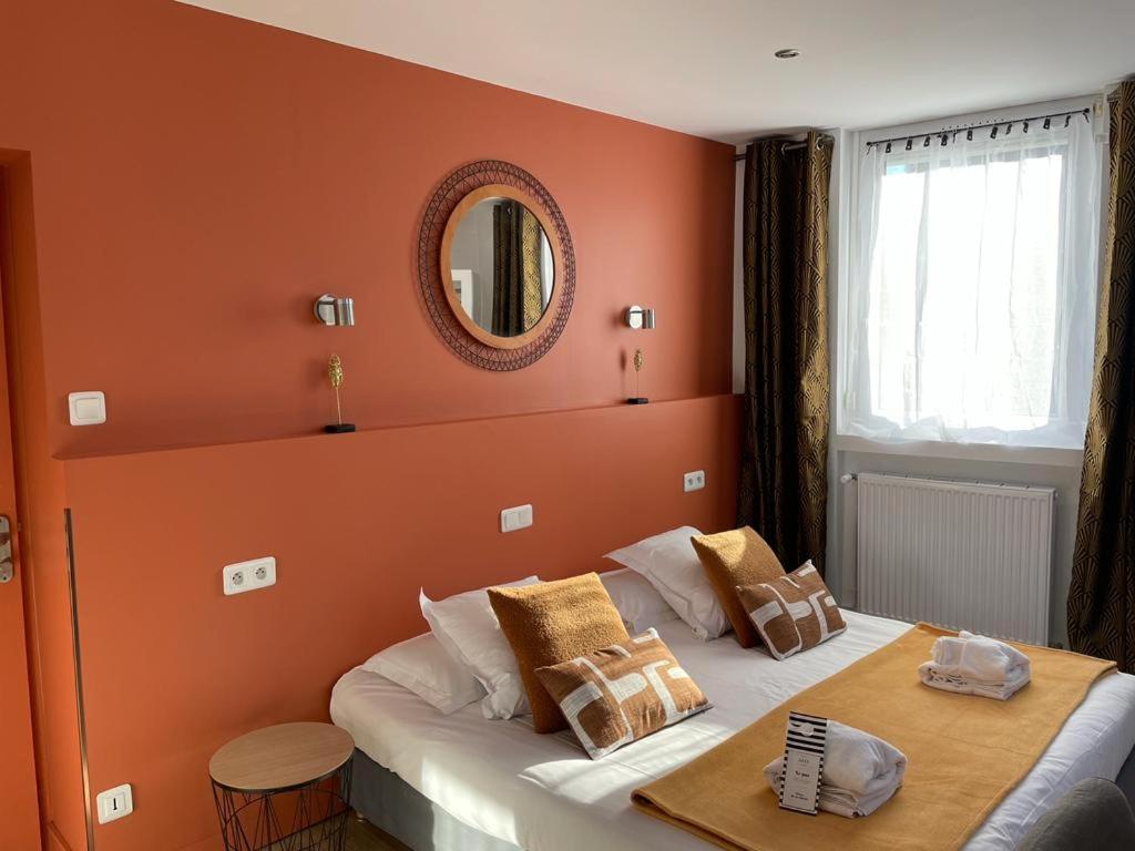 勒图凯-巴黎普拉日Hôtel Jules的一间卧室设有橙色的墙壁和一张带镜子的床