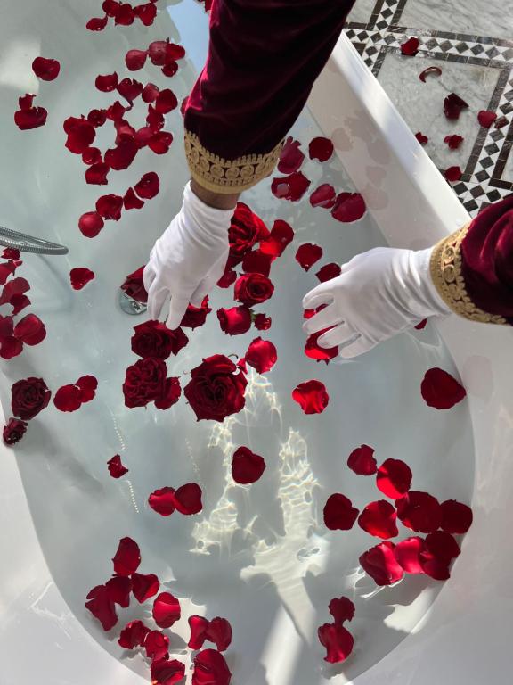 非斯Palais De Fès Suites & Spa的戴着白手套的人把红玫瑰放在桌子上